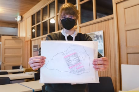 An ASP student proudly shows off a drawing of an airport.