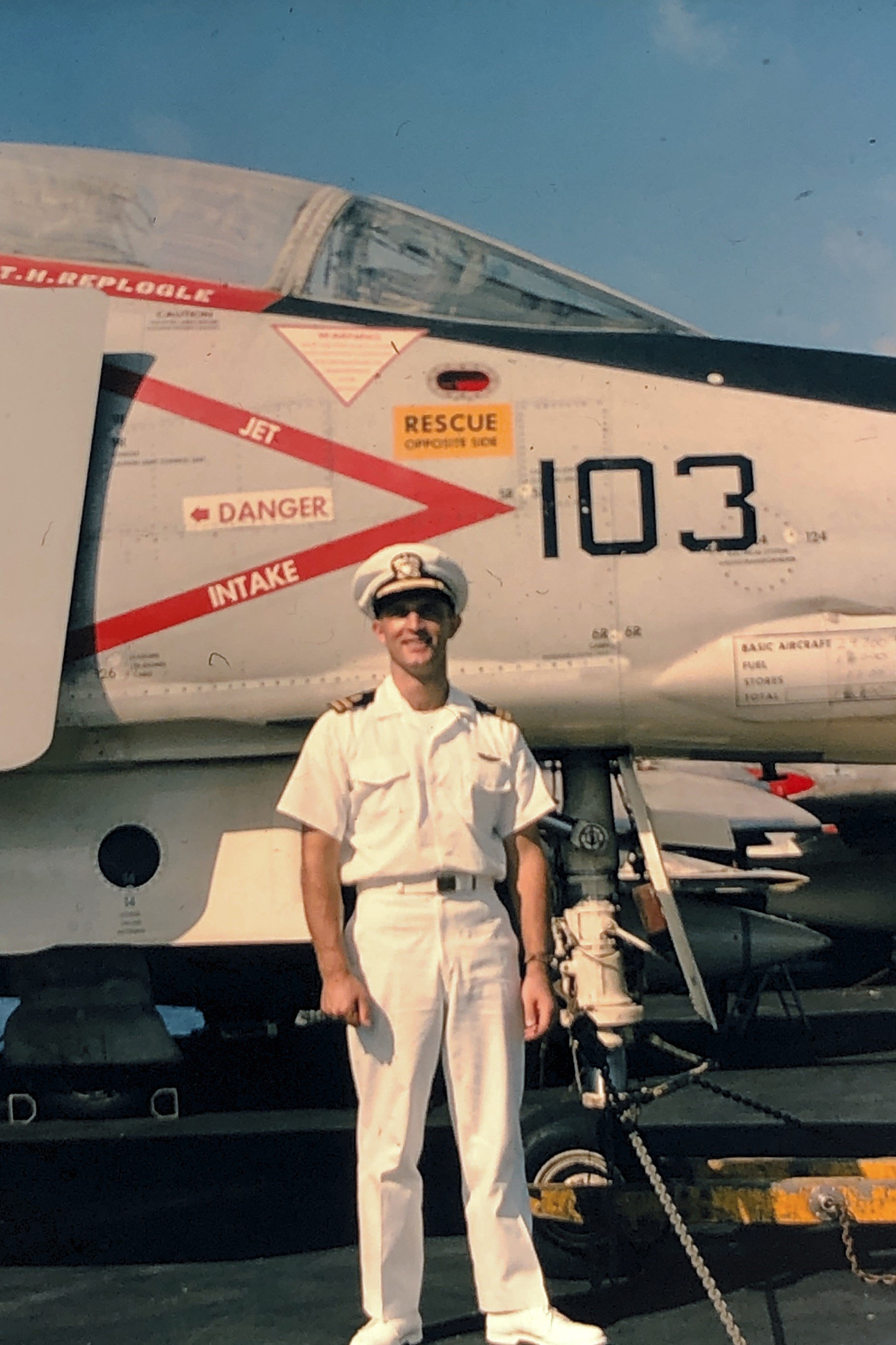 Featured image: A vintage photograph of Hank Davis, a flight surgeon, standing on the deck of an aircraft carrier in his full Navy dress uniform, smiling for the camera in the bright sunshine. Grey-painted jet fighters line up behind him. - Read full post: Stranger Than Fiction - Stories From A Flight Surgeon Part II