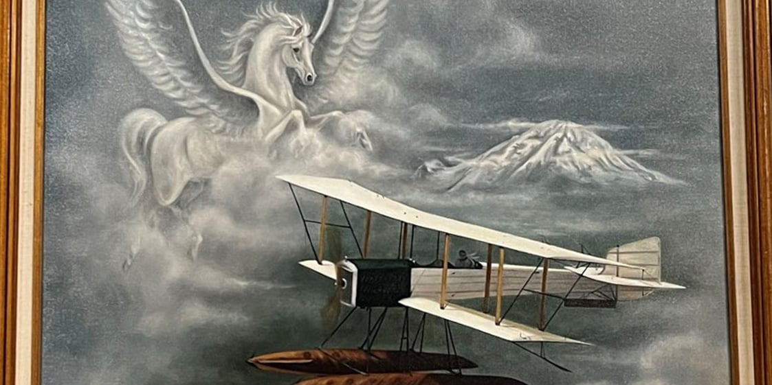 A painting of a Pegasus in the clouds over Mt. Rainier. A Boeing B&W flies by. Title: "Wings of Evolution 1916." 